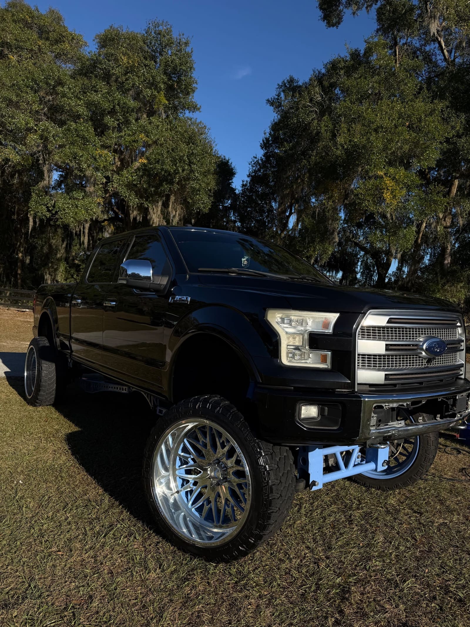 Black lifted pickup on grass, front three-quarter view