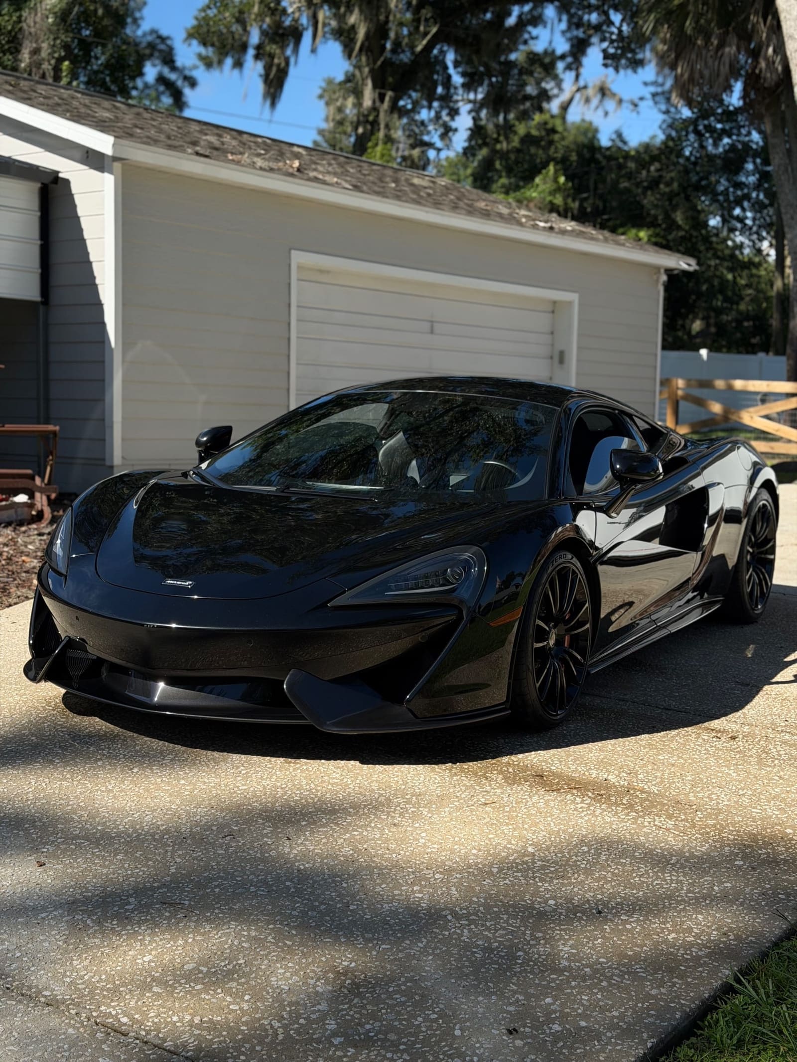 Black sports car on a driveway, front three-quarter view