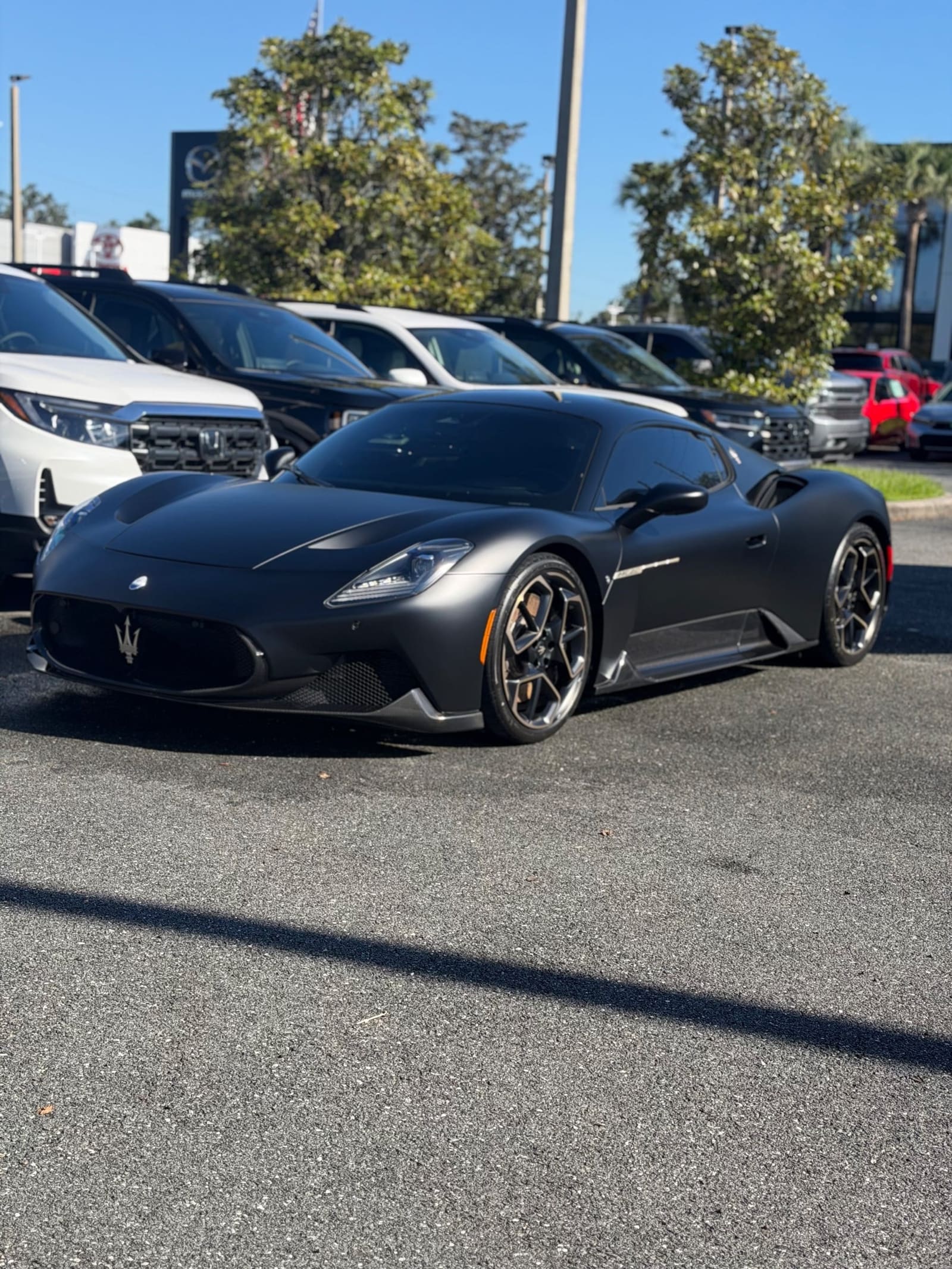 Black sports car in a parking lot, front three-quarter view