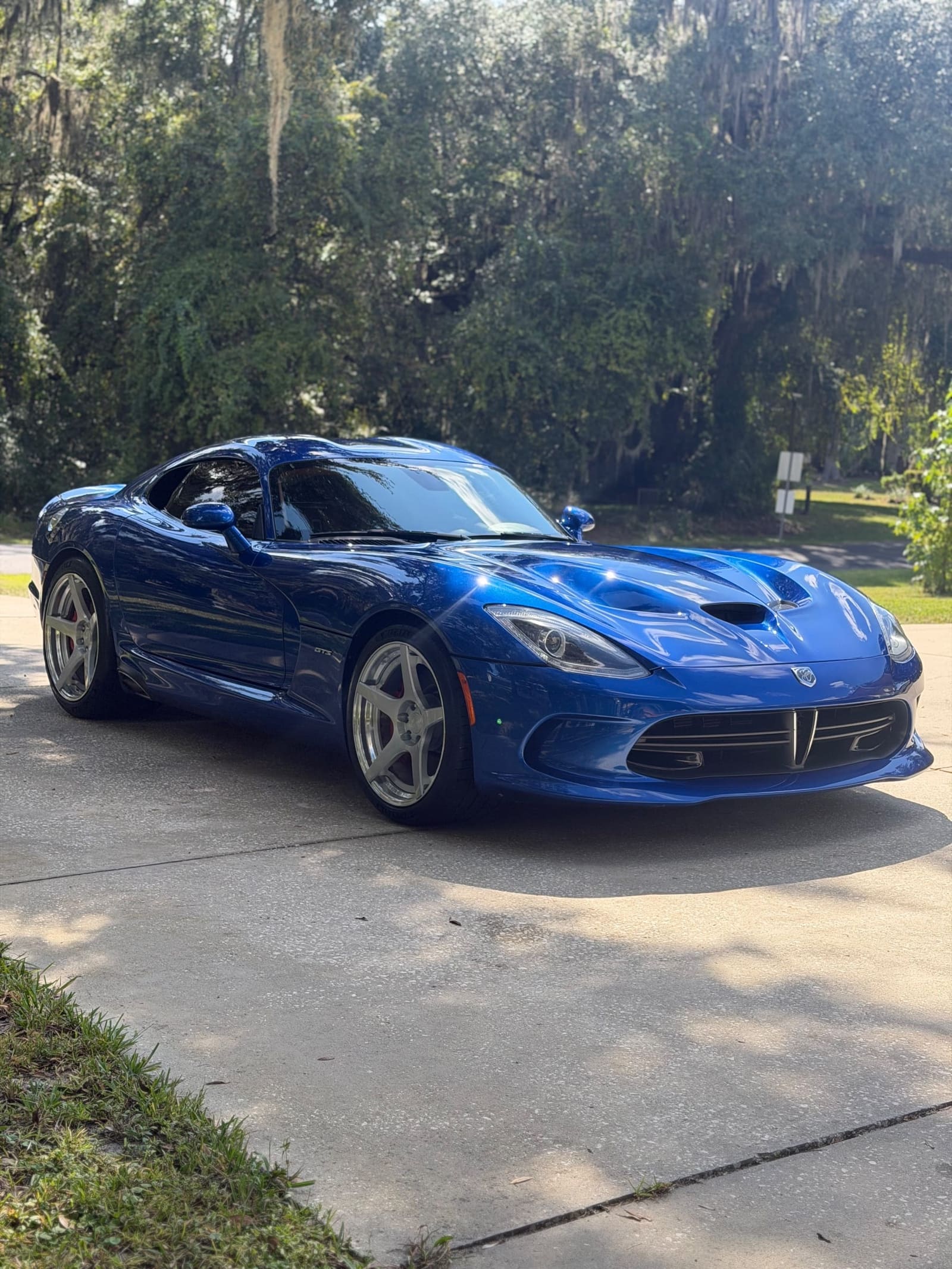 Blue sports car on a driveway, front three-quarter view