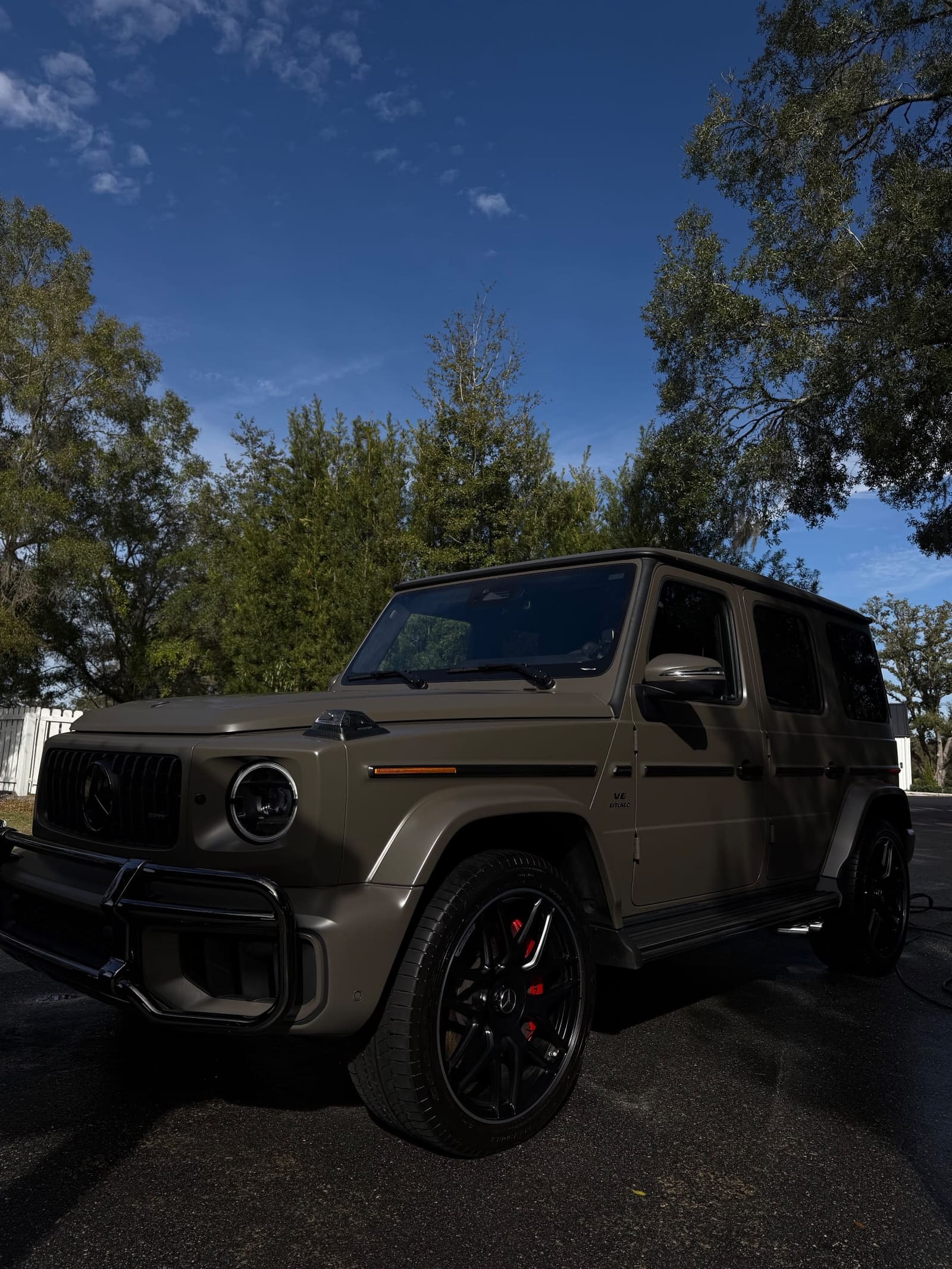 Mercedes-Benz G-Class on a tree-lined street, front three-quarter view
